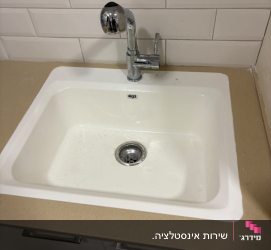 כיור מטבח לבן מותקן במשטח עם ברז כרום נשלף